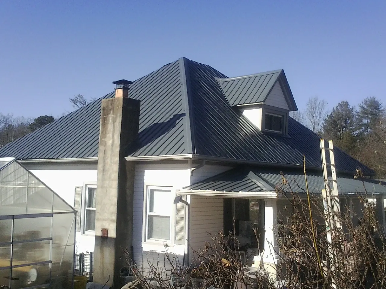 Dark blue standing seam metal roof on a white farmhouse with dormer — Slate & Tile Roof Repair by Roofing Brothers in Hookerton