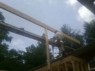 Carpenter setting a ridge beam over a new addition frame — Ice Dam Removal by Roofing Brothers in Hookerton