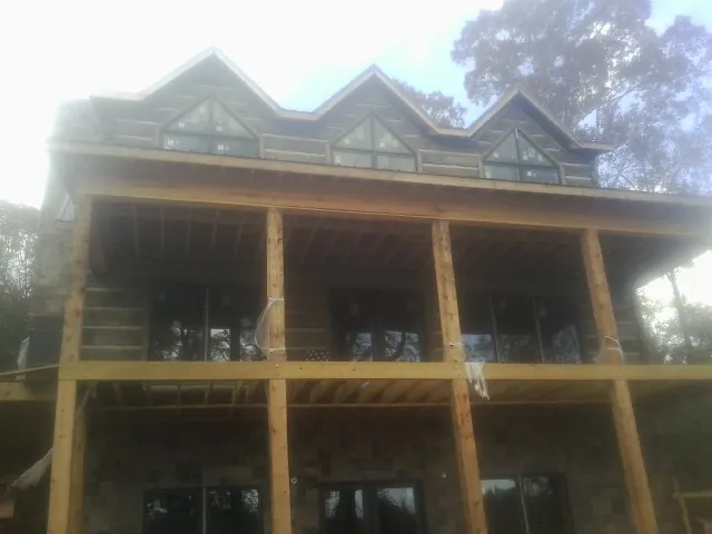Dormers and porch framing on a large log home under construction — Roof Coating work by our crew in Hookerton