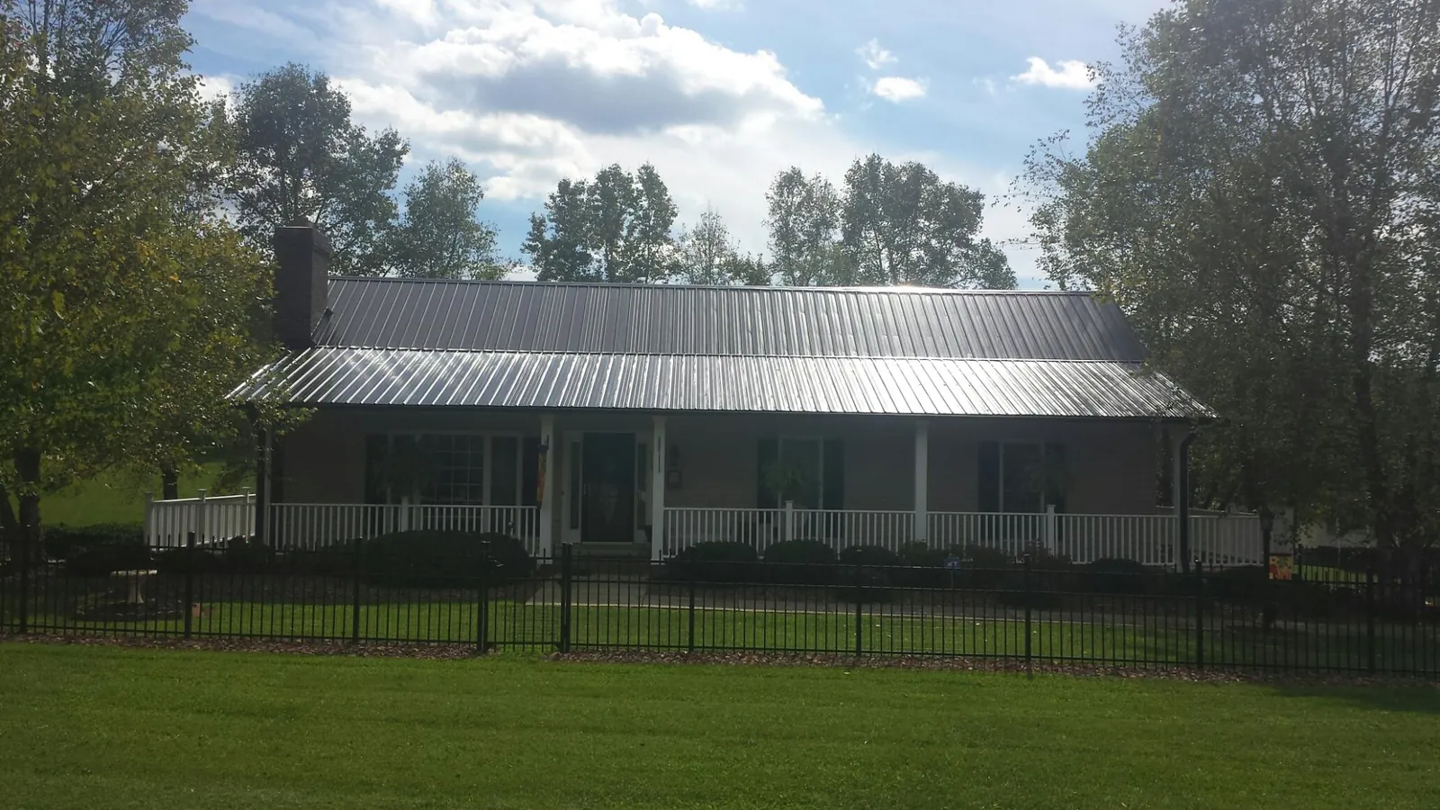 Gray metal roof on a brick ranch with a full width front porch — Gutter Guard Installation work by our crew in Hookerton
